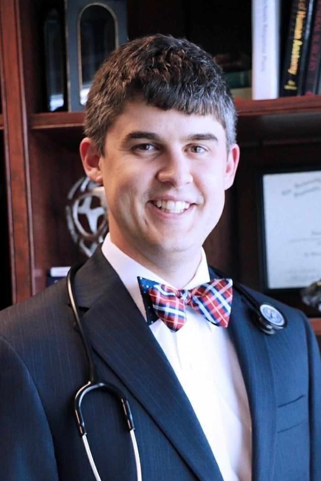 a man wearing a suit and tie smiling at the camera