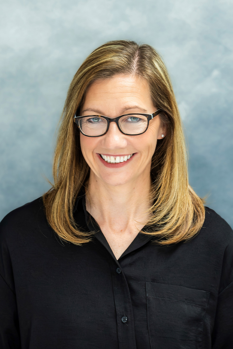 a person wearing glasses and smiling at the camera